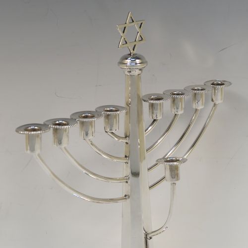 A very elegant Sterling Silver Hanukkah Menorah in a traditional style with rounded wire-work arms, having an octagonal panelled body with tapering sides, an original removable Shamus candle holder, and all sitting on a round stepped pedestal foot. This handsome silver menorah was made in Birmingham in 1957. The dimensions of this fine hand-made silver menorah are height 26 cms (10.25 inches), and spread across arms 21 cms (8.25 inches).   