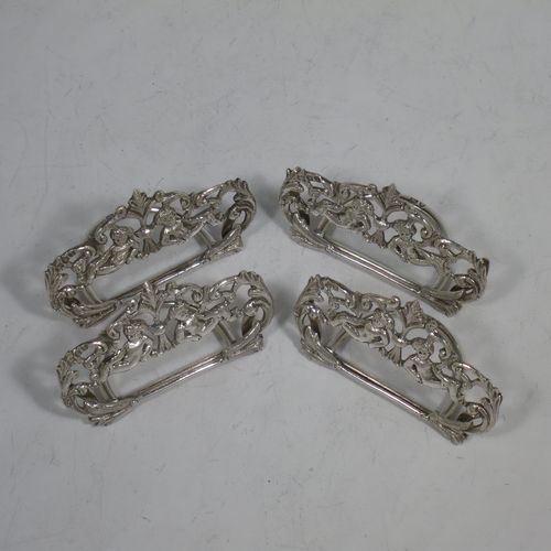 A very pretty Antique Victorian Sterling Silver set of four place card holders, having cast bodies with reclining cherubs over scroll and floral decoration, and sitting on half-circle wire-work bases. Made by Samuel Jacob of London in 1894. The dimensions of this fine set of antique silver place card holders are width 7 cms (2.75 inches), height 4 cms (1.5 inches), depth 3 cms (1.25 inches), and they weigh a total of approx. 106g (3.4 troy ounces).   