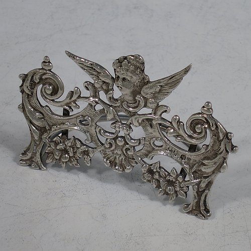 An Antique Sterling Silver set of four place card holders, having cast bodies with winged seraphims over scroll and floral decoration, and sitting on half-circle wire-work bases. Made by Stuart Clifford of London in 1904. The dimensions of this fine set of antique silver place card holders are width 7.5 cms (3 inches), height 5 cms (2 inches), depth 4 cms (1.5 inches), and they weigh a total of approx. 101g (3.3 troy ounces).    