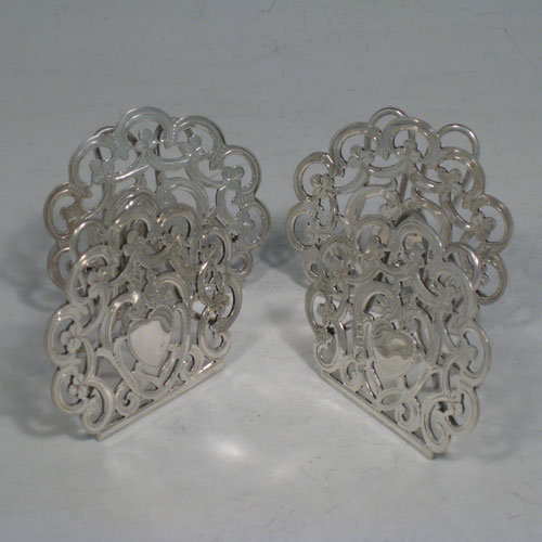 Antique Victorian sterling silver set of four menu or place card holders, having hand-pierced work with scrolls, three-leaf clovers, and heart-shaped cartouches. Please note that two are made in Birmingham in 1899, and two are marked sterling made in ca. 1890. Height 5 cms (2 inches), width 5 cms (2 inches). Total weight approx. 78g (2.5 troy ounces).