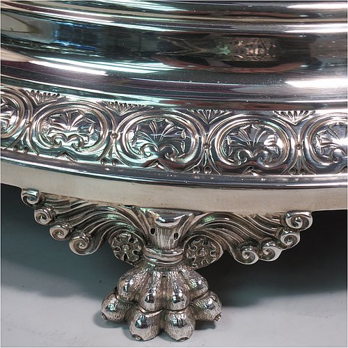 An Antique Edwardian Sterling Silver mirror plateau, having a round body with hand-chased floral decoration, a plain reeded border surrounding the mirror, all sitting on three cast foliate and lions-paw feet, and an original oak base underneath. Made by the Deakin Brothers of Sheffield in 1904. The dimensions of this fine hand-made antique silver mirror plateau are diameter 38 cms (15 inches), and height 9 cms (3.5 inches).    