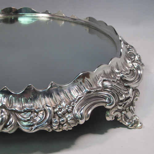 An elegant Antique Victorian silver-plated mirror plateau, having a round body, with hand-chased floral decoration, and sitting on four foliate feet. This beautiful antique silver plated mirror plateau was made in ca. 1880. The dimensions of this fine hand-made silver-plated mirror plateau are diameter 43 cms (17 inches), and height 9 cms (3.5 inches).