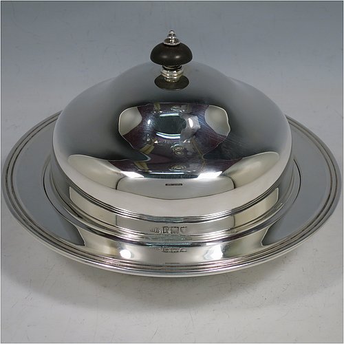 An Antique Sterling Silver muffin dish, having a plain round body with reeded border, a domed lift-off lid with wooden finial, an interior lift-out liner with space underneath for hot water or crushed ice, and sitting on a flat base. Made by Harrison Brothers & Howson of in 1912. The dimensions of this fine hand-made antique silver muffin dish are diameter 18.5 cms (7.3 inches), height 11.5 cms (4.5 inches), and it weighs approx. 486g (15.7 troy ounces).   