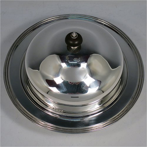 An Antique Sterling Silver muffin dish, having a plain round body with reeded border, a domed lift-off lid with wooden finial, an interior lift-out liner with space underneath for hot water or crushed ice, and sitting on a flat base. Made by Harrison Brothers & Howson of in 1912. The dimensions of this fine hand-made antique silver muffin dish are diameter 18.5 cms (7.3 inches), height 11.5 cms (4.5 inches), and it weighs approx. 486g (15.7 troy ounces).   