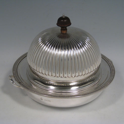    Antique Victorian sterling silver covered muffin dish, having a lift-off lid with half-fluted decoration and wooden finial, a removable plate (which can double as a serving dish) with a gadroon edge, and a deep base for hot water (or crushed ice) with two cast handles. Made by William Hutton and Sons of London in 1898. Height 15 cms (6 inches), diameter of removable plate 20 cms (8 inches). Total weight approx. 550g (17.7 troy ounces).