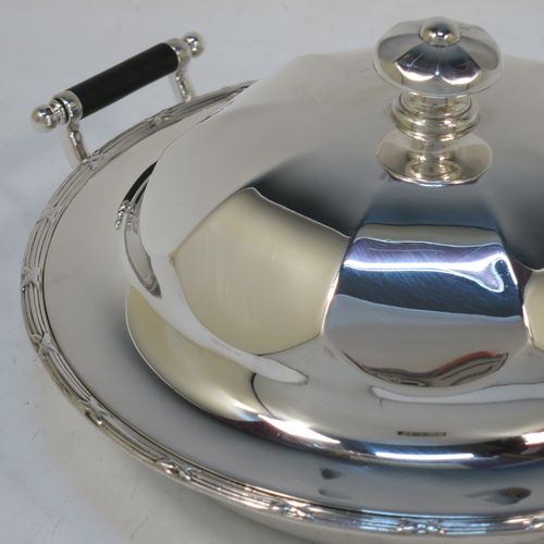 A handsome Antique Sterling Silver muffin dish, having a round body with an applied ribbon and reed border, with two side handles having black ebonised inserts, a domed and panelled lift-off lid with cast finial, and all sitting on a flat base. Made by James Dixon and Sons of Sheffield in 1911. The dimensions of this fine hand-made antique silver muffin dish are diameter 18 cms (7 inches), height 9 cms (3.5 inches), and it weighs approx. 330g (10.6 troy ounces).  