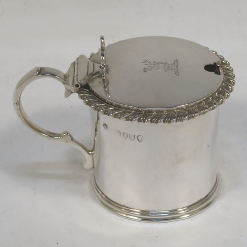 A handsome Antique Victorian Sterling Silver drum mustard, having a plain cylindrical body with a gadroon border, a hinged flat lid with hand-pierced thumb-piece, a scroll handle and a blue glass liner. This elegant silver mustard pot was made by William Evans of London in 1887. The dimensions of this fine hand-made silver mustard pot are height 7 cms (2.75 inches), diameter 6.5 cms (2.5 inches), and it weighs approx. 114g (3.7 troy ounces). Please note that this item is crested on the lid.