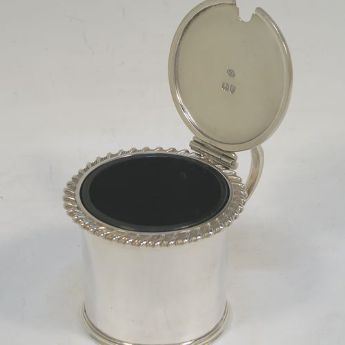 A handsome Antique Victorian Sterling Silver drum mustard, having a plain cylindrical body with a gadroon border, a hinged flat lid with hand-pierced thumb-piece, a scroll handle and a blue glass liner. This elegant silver mustard pot was made by William Evans of London in 1887. The dimensions of this fine hand-made silver mustard pot are height 7 cms (2.75 inches), diameter 6.5 cms (2.5 inches), and it weighs approx. 114g (3.7 troy ounces). Please note that this item is crested on the lid.