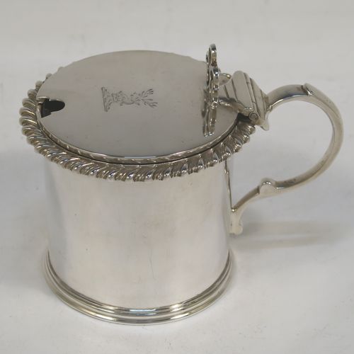 A handsome Antique Victorian Sterling Silver drum mustard, having a plain cylindrical body with a gadroon border, a hinged flat lid with hand-pierced thumb-piece, a scroll handle and a blue glass liner. This elegant silver mustard pot was made by William Evans of London in 1887. The dimensions of this fine hand-made silver mustard pot are height 7 cms (2.75 inches), diameter 6.5 cms (2.5 inches), and it weighs approx. 114g (3.7 troy ounces). Please note that this item is crested on the lid.