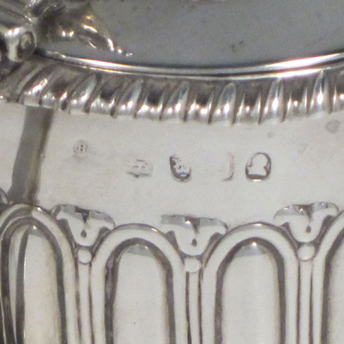 Antique Georgian Regency sterling silver mustard pot, having a round body with hand-chased fluted straight sides, a gadroon-edged border, a hinged lid with shell thumb-piece, a blue glass liner and scroll handle, all sitting on a flat base. Made by Rebecca Emes and Edward Barnard of London in 1817. The dimensions of this fine hand-made silver mustard pot are height 6.5 cms (2.5 inches), diameter 7 cms (2.75 inches), and it weighs approx. 146g (4.7 troy ounces).