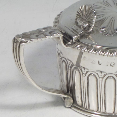 Antique Georgian Regency sterling silver mustard pot, having a round body with hand-chased fluted straight sides, a gadroon-edged border, a hinged lid with shell thumb-piece, a blue glass liner and scroll handle, all sitting on a flat base. Made by Rebecca Emes and Edward Barnard of London in 1817. The dimensions of this fine hand-made silver mustard pot are height 6.5 cms (2.5 inches), diameter 7 cms (2.75 inches), and it weighs approx. 146g (4.7 troy ounces).