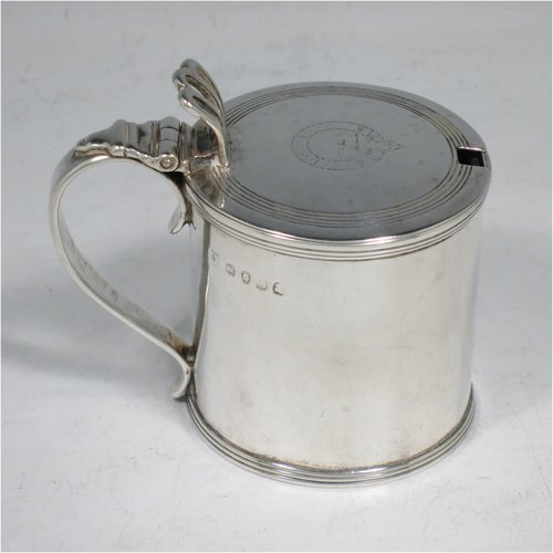 An Antique Georgian Sterling Silver drum mustard pot, having a plain cylindrical body, with applied reeded borders, a hinged lid with pierced thumb-piece, a plain scroll handle, and an internal blue glass liner. Made by Rebecca Emes & Edward Barnard I of London in 1818. The dimensions of this fine hand-made antique silver mustard pot are height 8 cms (3 inches), diameter 6 cms (2.3 inches), and it weighs approx. 144g (4.6 troy ounces). Please note that this item has an engraved crest on the top of the lid.  