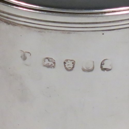 An Antique Georgian Sterling Silver drum mustard pot, having a plain cylindrical body, with applied reeded borders, a hinged lid with pierced thumb-piece, a plain scroll handle, and an internal blue glass liner. Made by Rebecca Emes & Edward Barnard I of London in 1818. The dimensions of this fine hand-made antique silver mustard pot are height 8 cms (3 inches), diameter 6 cms (2.3 inches), and it weighs approx. 144g (4.6 troy ounces). Please note that this item has an engraved crest on the top of the lid.  