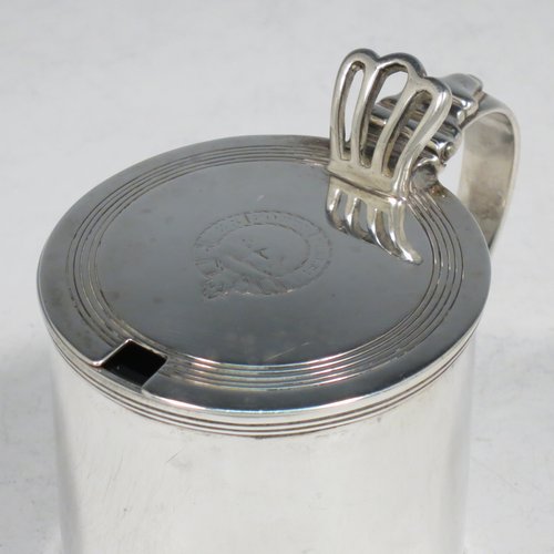 An Antique Georgian Sterling Silver drum mustard pot, having a plain cylindrical body, with applied reeded borders, a hinged lid with pierced thumb-piece, a plain scroll handle, and an internal blue glass liner. Made by Rebecca Emes & Edward Barnard I of London in 1818. The dimensions of this fine hand-made antique silver mustard pot are height 8 cms (3 inches), diameter 6 cms (2.3 inches), and it weighs approx. 144g (4.6 troy ounces). Please note that this item has an engraved crest on the top of the lid.  