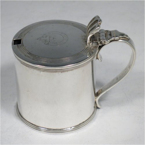 An Antique Georgian Sterling Silver drum mustard pot, having a plain cylindrical body, with applied reeded borders, a hinged lid with pierced thumb-piece, a plain scroll handle, and an internal blue glass liner. Made by Rebecca Emes & Edward Barnard I of London in 1818. The dimensions of this fine hand-made antique silver mustard pot are height 8 cms (3 inches), diameter 6 cms (2.3 inches), and it weighs approx. 144g (4.6 troy ounces). Please note that this item has an engraved crest on the top of the lid.  