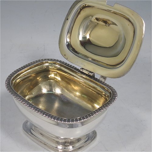 An Antique Georgian Sterling Silver mustard pot, having a plain rectangular baluster body with rounded corners, a hinged domed lid with ball finial, a gold-gilt interior, and a flat looped handle, all sitting on a pedestal foot. Made in  London in 1814. The dimensions of this fine hand-made antique silver mustard pot are height 7.3 cms (3 inches), length 10 cms (4 inches), and it weighs approx. 185g (6 troy ounces). Please note that this item is crested on the lid.   