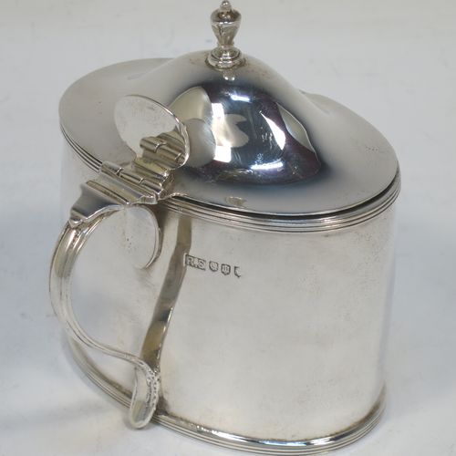 A very handsome and large Scottish Sterling Silver mustard pot, having a plain oval body with slightly curved sides, with applied reeded borders, a domed lid with an urn-shaped finial, a scroll side-handle with plain oval thumb-piece, and a fitted blue glass liner. Made by Robert Sawers Ltd of Edinburgh in 1936. The dimensions of this fine hand-made Scottish silver mustard pot are height 8.5 cms (3.3 inches), length 8 cms (3 inches), depth  (inc. handle) 8 cms (3 inches), and it weighs approx. 108g (3.5 troy ounces).