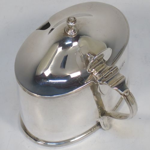 A very handsome and large Scottish Sterling Silver mustard pot, having a plain oval body with slightly curved sides, with applied reeded borders, a domed lid with an urn-shaped finial, a scroll side-handle with plain oval thumb-piece, and a fitted blue glass liner. Made by Robert Sawers Ltd of Edinburgh in 1936. The dimensions of this fine hand-made Scottish silver mustard pot are height 8.5 cms (3.3 inches), length 8 cms (3 inches), depth  (inc. handle) 8 cms (3 inches), and it weighs approx. 108g (3.5 troy ounces).