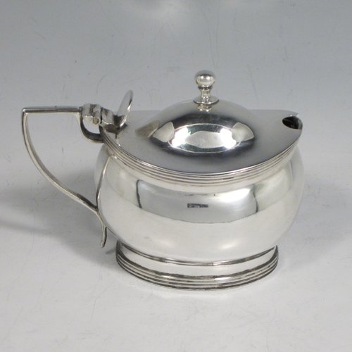 Antique Georgian sterling silver mustard pot, having a plain oval baluster body, a hinged domed lid with thumb-piece and ball finial, with applied reeded borders, a reeded scroll handle, a blue glass liner, all sitting on a flat base. Made by John Gold of London in 1801. The dimensions of this fine hand-made silver mustard pot are height 8 cms (3 inches), length 11 cms (4.25 inches), width 6 cms (2.25 inches), and it weighs approx. 115g (3.7 troy ounces).   