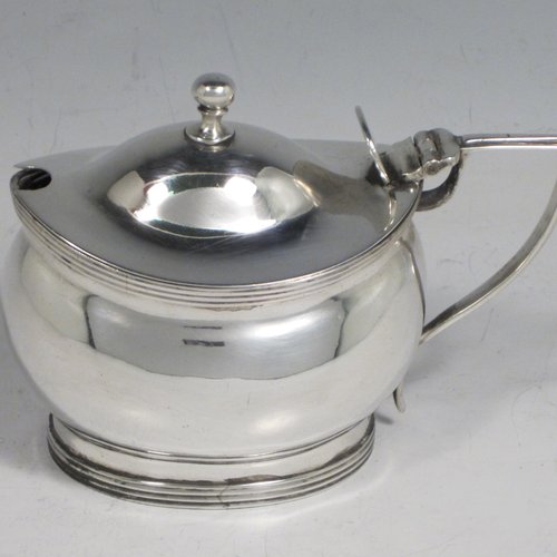 Antique Georgian sterling silver mustard pot, having a plain oval baluster body, a hinged domed lid with thumb-piece and ball finial, with applied reeded borders, a reeded scroll handle, a blue glass liner, all sitting on a flat base. Made by John Gold of London in 1801. The dimensions of this fine hand-made silver mustard pot are height 8 cms (3 inches), length 11 cms (4.25 inches), width 6 cms (2.25 inches), and it weighs approx. 115g (3.7 troy ounces).   