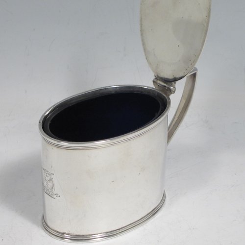 Antique Georgian sterling silver drum mustard pot, having a plain oval body with applied reeded borders, a flat hinged lid with thumb-piece, a scroll handle, and a blue-glass liner. Made by John Emes of London in 1804. The dimensions of this fine hand-made silver mustard pot are length 10 cms (4 inches), height 7.5 cms (3 inches), width 5 cms (2 inches), and it weighs approx. 137g (4.4 troy ounces). Please note that this item is crested.