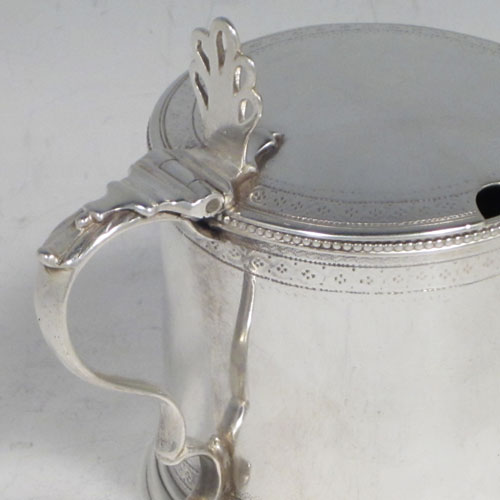 Antique Georgian sterling silver drum mustard pot, having a round body with straight sides, with subtle hand-engraved bands of floral decoration, a bead-edged top border, a hinged lid with pierced thumb-piece, a blue glass liner and scroll handle, all sitting on a flat base. Made by Robert Hennell of London in 1784. The dimensions of this fine hand-made silver mustard pot are height 8 cms (3 inches), diameter 6 cms (2.3 inches), and it weighs approx. 110g (3.5 troy ounces).