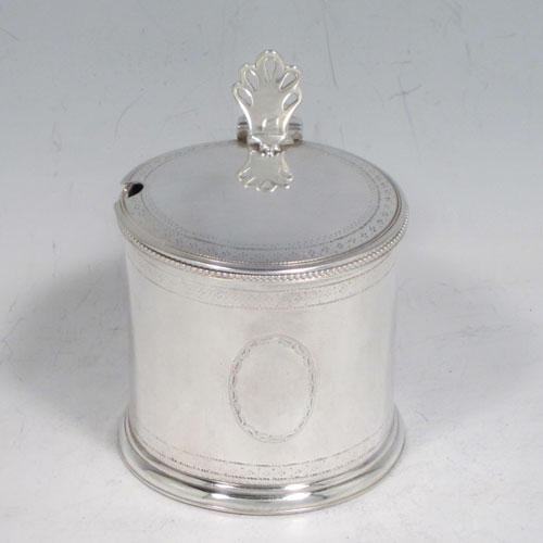 Antique Georgian sterling silver drum mustard pot, having a round body with straight sides, with subtle hand-engraved bands of floral decoration, a bead-edged top border, a hinged lid with pierced thumb-piece, a blue glass liner and scroll handle, all sitting on a flat base. Made by Robert Hennell of London in 1784. The dimensions of this fine hand-made silver mustard pot are height 8 cms (3 inches), diameter 6 cms (2.3 inches), and it weighs approx. 110g (3.5 troy ounces).