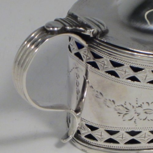 Antique Georgian sterling silver mustard pot, having an oval body with straight sides, with hand-pierced and engraved floral decoration, a hinged and domed lid with finial, a scroll handle, a blue glass liner, and all sitting on a flat base. Made by Joseph Preedy of London in 1793. The dimensions of this fine hand-made silver mustard pot are height 6 cms (2.3 inches), length 11 cms (4.3 inches), width 5 cms (2 inches), and it weighs approx. 83g (2.7 troy ounces).   