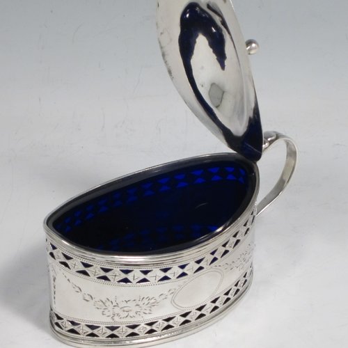 Antique Georgian sterling silver mustard pot, having an oval body with straight sides, with hand-pierced and engraved floral decoration, a hinged and domed lid with finial, a scroll handle, a blue glass liner, and all sitting on a flat base. Made by Joseph Preedy of London in 1793. The dimensions of this fine hand-made silver mustard pot are height 6 cms (2.3 inches), length 11 cms (4.3 inches), width 5 cms (2 inches), and it weighs approx. 83g (2.7 troy ounces).   