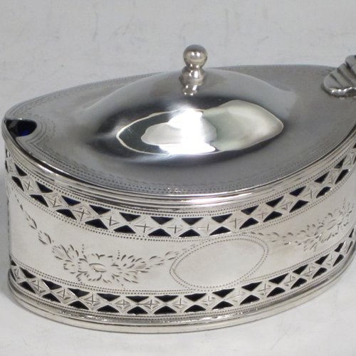 Antique Georgian sterling silver mustard pot, having an oval body with straight sides, with hand-pierced and engraved floral decoration, a hinged and domed lid with finial, a scroll handle, a blue glass liner, and all sitting on a flat base. Made by Joseph Preedy of London in 1793. The dimensions of this fine hand-made silver mustard pot are height 6 cms (2.3 inches), length 11 cms (4.3 inches), width 5 cms (2 inches), and it weighs approx. 83g (2.7 troy ounces).   