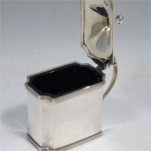 An Antique Edwardian Sterling Silver mustard pot, having a plain straight-sided body with cut-corners and applied reeded borders, a hinged domed lid with cast scroll thumb-piece and urn finial, a plain scroll handle, an original blue-glass liner, and sitting on a flat base. Made by Zachariah Barraclough & Sons of Chester in 1907. The dimensions of this fine hand-made antique silver mustard pot are length 9 cms (3.5 inches), height 9 cms (3.5 inches), and it weighs approx. 136g (4.4 troy ounces).    