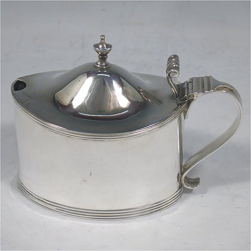 An Antique Georgian Sterling Silver mustard pot, having a plain oval straight-sided body, with applied reeded borders, a hinged domed lid with cast thumb-pieced and finial, a reeded scroll handle, a blue-glass liner, and sitting on a flat base. Made by Frances Purton & Thomas Johnson of London in 1794. The dimensions of this fine hand-made antique silver mustard pot are length 11 cms (4.25 inches), height 8.5 cms (3.3 inches), and it weighs approx. 125g (4 troy ounces).