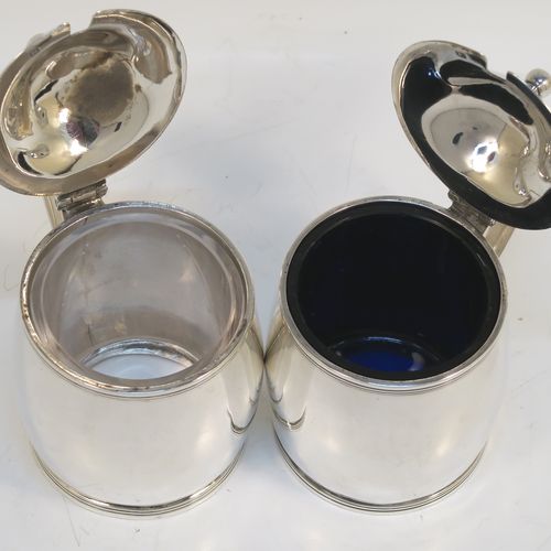 A rare and very elegant Antique Georgian Sterling Silver pair of drum mustard pots, having plain round bodies with slightly convex sides, with applied reeded top and bottom borders, domed hinged lids with plain oval thumb-pieces and ball finials, scroll side-handles, and a blue-glass and clear glass liner. These beautiful silver mustard pots were made by John Emes of London in 1802. The dimensions of these fine hand-made antique silver mustard pots are length 8.5 cms (3.3 inches), height 8.5 cms (3.3 inches), diameter of bodies 6 cms (2.25 inches), and they weigh a total of approx. 213g (6.9 troy ounces).  