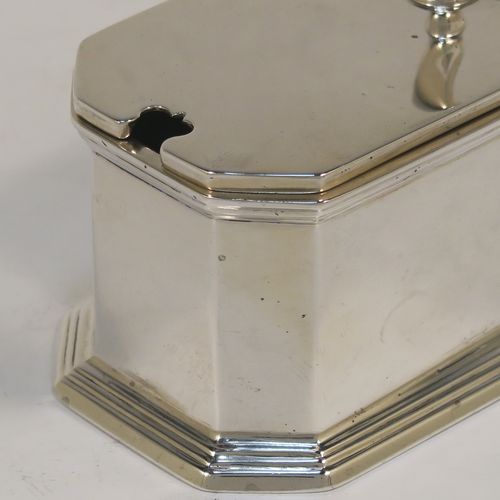 A very handsome Sterling Silver mustard pot, having a plain straight-sided body with chamfered corners and applied reeded borders, a hinged flat  lid with cast scroll thumb-piece, a plain scroll handle, an original blue-glass liner, and sitting on a collet foot. This elegant silver mustard pot was made by Goldsmiths and Silversmiths of London in 1929. The dimensions of this fine hand-made silver mustard pot are length 10 cms (4 inches), height 7 cms (2.7 inches), and it weighs approx. 142g (4.6 troy ounces).  