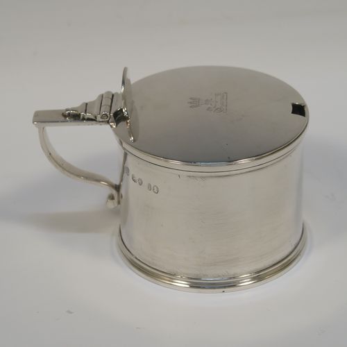 A large and very elegant Antique Georgian Sterling Silver drum mustard, having a plain cylindrical body, with applied reeded borders, a hinged flat lid with a plain oval thumb-piece, a scroll handle and a blue glass liner. This handsome antique silver mustard pot was made by the Barnard Brothers of London in 1829. The dimensions of this fine hand-made antique silver mustard pot are height 7 cms (2.75 inches), diameter 7.5 cms (3 inches), and it weighs approx. 154g (5 troy ounces). Please note that this item is crested on the lid.  