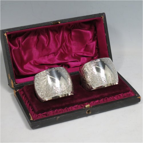 An Antique Victorian Sterling Silver pair of napkin rings, having round bellied bodies with hand-engraved floral decoration surrounding vacant cartouches, all in their original maroon satin and velvet-lined presentation box. Please note that one is engraved with Ivy, and the other with Gingko leaves. Made by Martin and Hall of Sheffield in 1893. The dimensions of these fine hand-made silver napkin rings are diameter 4.5 cms (1.75 inches), height 3.5 cms (1.3 inch), and they weigh a total of approx. 75g (2.4 troy ounces).   