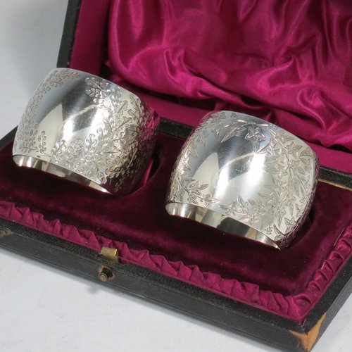 An Antique Victorian Sterling Silver pair of napkin rings, having round bellied bodies with hand-engraved floral decoration surrounding vacant cartouches, all in their original maroon satin and velvet-lined presentation box. Please note that one is engraved with Ivy, and the other with Gingko leaves. Made by Martin and Hall of Sheffield in 1893. The dimensions of these fine hand-made silver napkin rings are diameter 4.5 cms (1.75 inches), height 3.5 cms (1.3 inch), and they weigh a total of approx. 75g (2.4 troy ounces).   