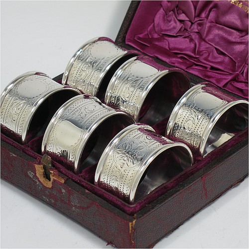 An Antique Victorian Sterling Silver set of six napkin rings, having round bodies with straight sides, hand-engraved floral decoration and vacant round cartouches, with applied plain borders, all in their original purple satin and velvet-lined presentation box. Made by Hilliard and Thomason of Chester in 1897. The dimensions of these fine hand-made antique silver napkin rings are diameter 4 cms (1.5 inches), height 2.5 cms (1 inch), and they weigh a total of approx. 113g (3.6 troy ounces). Please note that the box lock mechanism is slightly damaged.