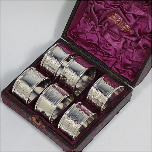 An Antique Victorian Sterling Silver set of six napkin rings, having round bodies with straight sides, hand-engraved floral decoration and vacant round cartouches, with applied plain borders, all in their original purple satin and velvet-lined presentation box. Made by Hilliard and Thomason of Chester in 1897. The dimensions of these fine hand-made antique silver napkin rings are diameter 4 cms (1.5 inches), height 2.5 cms (1 inch), and they weigh a total of approx. 113g (3.6 troy ounces). Please note that the box lock mechanism is slightly damaged.