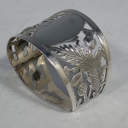 A Sterling Silver set of six napkin rings, having half-circular bodies with flat bases, with hand-pierced and engraved floral Scottish thistle decoration surrounding oval cartouches, all in their original green satin and velvet-lined presentation box. Made by Robert Comyns of Birmingham in 1919. The dimensions of these fine hand-made silver napkin rings are width 5 cms (2 inches), depth 4 cms (1.5 inches), height 3.5 cms (1.3 inches), and they weigh a total of approx. 160g (5.2 troy ounces).   