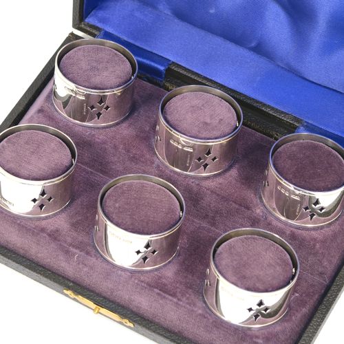 A pretty Sterling Silver set of six napkin rings, having round bodies with straight sides, with hand-pierced diamond style decoration, all in their original dark blue satin and purple velvet-lined presentation box. These beautiful silver napkin rings were made by Louis Simpson of London in 1946. The dimensions of these fine hand-made silver napkin rings are diameter 4.5 cms (1.75 inches), height 2.5 cms (1 inch), and they weigh a total of approx. 170g (5.5 troy ounces).   