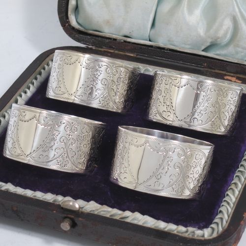 A very pretty Antique Victorian Sterling Silver set of four napkin rings, having round bodies with straight sides, hand-engraved floral and scroll decoration with two vacant shaped shield style cartouches, all in their original light blue satin and dark blue velvet-lined presentation box. Made by Walker and Hall of Sheffield in 1894. The dimensions of these fine hand-made antique silver-plated napkin rings are diameter 4.5 cms (1.75 inches), height 2.5 cms (1 inch), and they weigh a total of approx. 119g (3.8 troy ounces).   