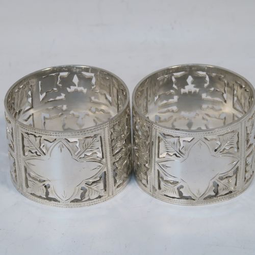 A very pretty and heavy Antique Victorian Art Nouveau style Sterling Silver pair of napkin rings, having round straight-sided bodies with hand-pierced and engraved floral decoration, all in their original dark blue satin and velvet-lined presentation box. These beautiful antique silver napkin rings were made by the Rolason Brothers of Birmingham in 1900. The dimensions of these fine hand-made antique silver napkin rings are diameter 4.5 cms (1.75 inches), height 3 cms (1.25 inches), and they weigh a total of approx. 77g (2.5 troy ounces).  