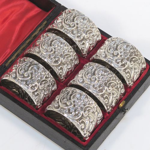 A very pretty Antique Victorian Sterling Silver set of six napkin rings, having round straight-sided bodies, with hand-chased floral, scroll and fluted decoration, and all in their original red satin and velvet-lined presentation box. These beautiful silver napkin rings were made by Henry Matthews of Birmingham in 1901. The dimensions of these fine hand-made antique silver napkin rings are diameter 4.5 cms (1.75 inches), height 2.5 cms (1 inch), and they weigh a total of approx. 120g (3.9 troy ounces).  