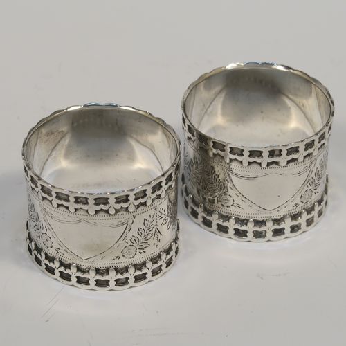 A very unusual Antique Edwardian Sterling Silver pair of napkin rings, having straight sided round bodies with applied fleur-de-lis borders, and hand-engraved floral decoration surrounding a vacant cartouche. These beautiful silver napkin rings were made by Thomas Hayes of Birmingham in 1906. The dimensions of these fine hand-made silver napkin rings are diameter 4.5 cms (1.75 inches), height 3.5 cms (1.3 inches), and they weigh a total of approx. 62g (2 troy ounces).  