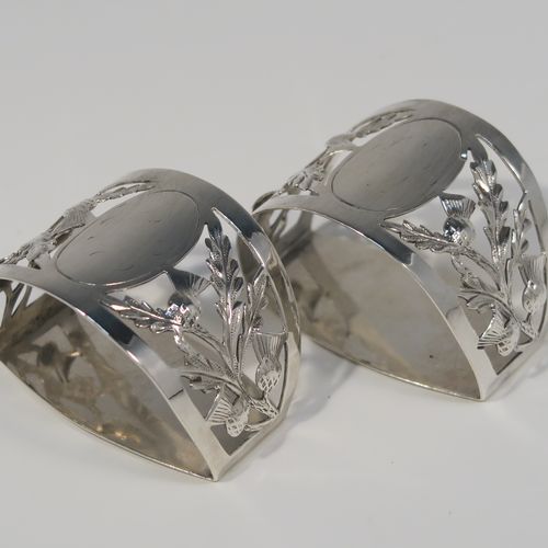 A very pretty Antique Art Nouveau style Sterling Silver pair of napkin rings, having semi-circular bodies with flat sides, with hand-pierced Scottish Thistle floral decoration, surrounding vacant oval cartouches. These beautiful antique silver napkin rings were made by Walker and Hall of Sheffield in 1911. The dimensions of these fine hand-made antique silver napkin rings are length 5 cms (2 inches), height 3.5 cms (1.3 inches), and they weigh a total of approx. 56g (1.8 troy ounces).   