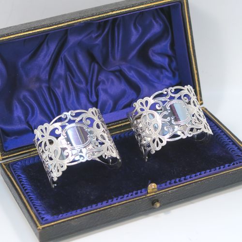 A very pretty Antique Edwardian Art Nouveau style Sterling Silver pair of napkin rings, having round straight-sided bodies with hand-pierced and engraved floral and scroll decoration, all in their original dark blue satin and velvet-lined presentation box. These beautiful antique silver napkin rings were made by George Rhoden of Sheffield in 1909. The dimensions of these fine hand-made antique silver napkin rings are diameter 4.5 cms (1.75 inches), height 4 cms (1.5 inches), and they weigh a total of approx. 63g (2 troy ounces).   