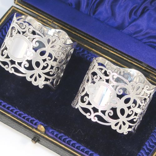 A very pretty Antique Edwardian Art Nouveau style Sterling Silver pair of napkin rings, having round straight-sided bodies with hand-pierced and engraved floral and scroll decoration, all in their original dark blue satin and velvet-lined presentation box. These beautiful antique silver napkin rings were made by George Rhoden of Sheffield in 1909. The dimensions of these fine hand-made antique silver napkin rings are diameter 4.5 cms (1.75 inches), height 4 cms (1.5 inches), and they weigh a total of approx. 63g (2 troy ounces).   