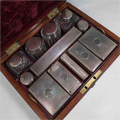 An Antique Victorian Sterling Silver travelling Necessaire, having two cologne bottles, two large bottles, two small bottles, a hair brush, two clothes brushes, an inkwell, a shaving brush, a soap box, a folding desk mirror, and internal space for letters, pens, and jewellery, all fitted in an original maroon velvet-lined oak box with brass fittings. All silver items have engine-turned decoration with central cartouches that are crested, and are made by Thomas Johnson of London in 1862. The dimensions of the solid oak box are 30.5 cms (12 inches), height 14 cms (5.5 inches), and width 24 cms (9.5 inches). Please note that the box is slightly damaged, but otherwise in excellent condition. All silver and crystal items are original with full matching hallmarks.