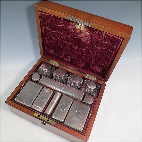 An Antique Victorian Sterling Silver travelling Necessaire, having two cologne bottles, two large bottles, two small bottles, a hair brush, two clothes brushes, an inkwell, a shaving brush, a soap box, a folding desk mirror, and internal space for letters, pens, and jewellery, all fitted in an original maroon velvet-lined oak box with brass fittings. All silver items have engine-turned decoration with central cartouches that are crested, and are made by Thomas Johnson of London in 1862. The dimensions of the solid oak box are 30.5 cms (12 inches), height 14 cms (5.5 inches), and width 24 cms (9.5 inches). Please note that the box is slightly damaged, but otherwise in excellent condition. All silver and crystal items are original with full matching hallmarks.